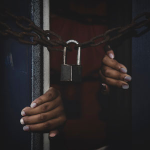 Two people in the prison putting their hands on the door - Serving Immigrants