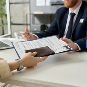 A woman handing her immigration application to an officer - Serving Immigrants