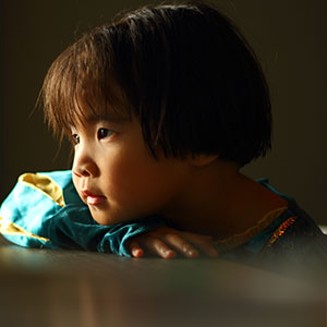 A child leaning on a table - Serving Immigrants