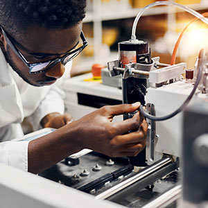 A man in a lab operating a machine - Serving Immigrants