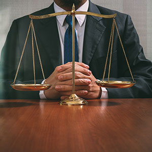 A person in a suit and tie sitting at a table with a scale - Serving Immigrants