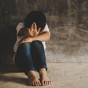 A women sitting on the floor with their hands over their face - Serving Immigrants