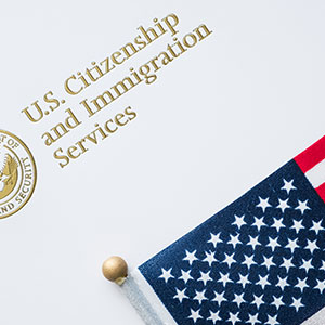 Logo of US Citizenship and Immigration Services, featuring American flag - Serving Immigrants