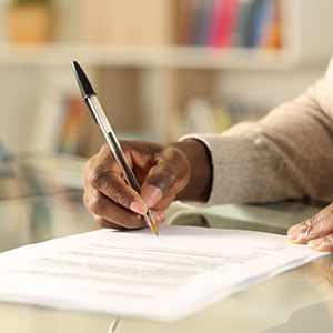 A person signing a document - Serving Immigrants