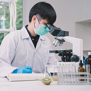 A person in a lab looking through a microscope - Serving Immigrants