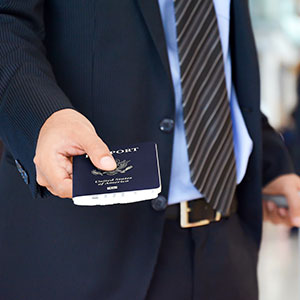 A man in suit holding a passport - Serving Immigrants