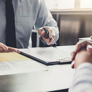 A person holding a pen over a document - Serving Immigrants