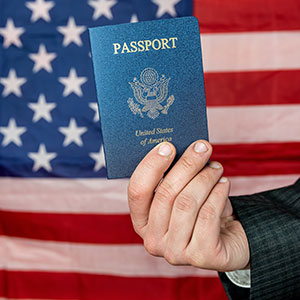 A person holding a passport with flag in background - Serving Immigrants