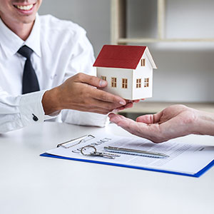 A person handing a house to another person - Serving Immigrants