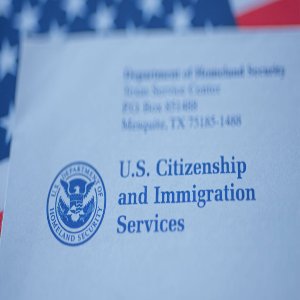 Close-up of a document with a flag in the background - Serving Immigrants