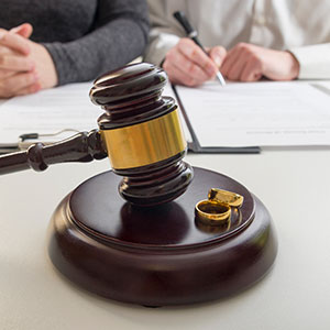 A gavel and wedding rings on a table - Serving Immigrants