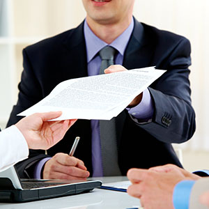 A man handing a piece of paper to a woman - Serving Immigrants