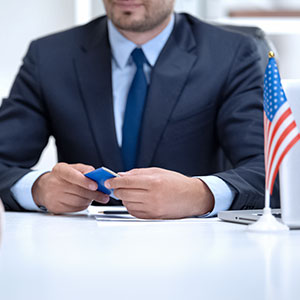 A person in a suit holding a visa - Serving Immigrants