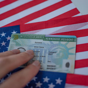 A man holding a card over a flag - Serving Immigrants